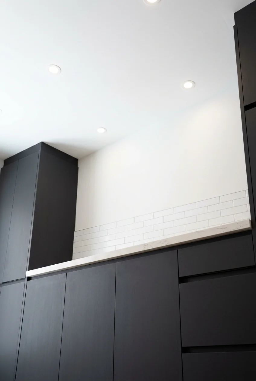 Crisp white ceiling balancing matte charcoal kitchen cabinets.