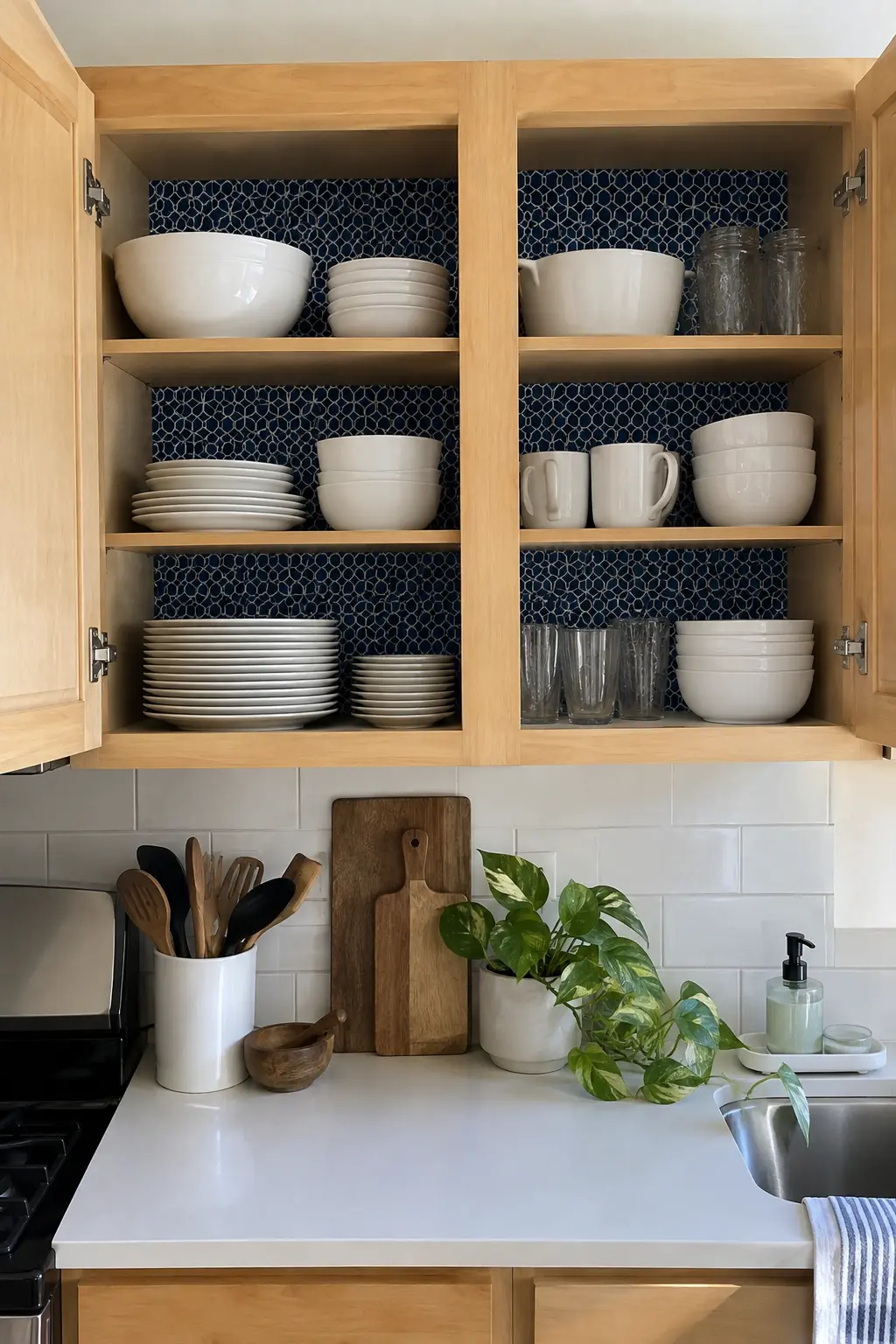 Open kitchen cabinet backed with removable geometric liner and everyday dishes