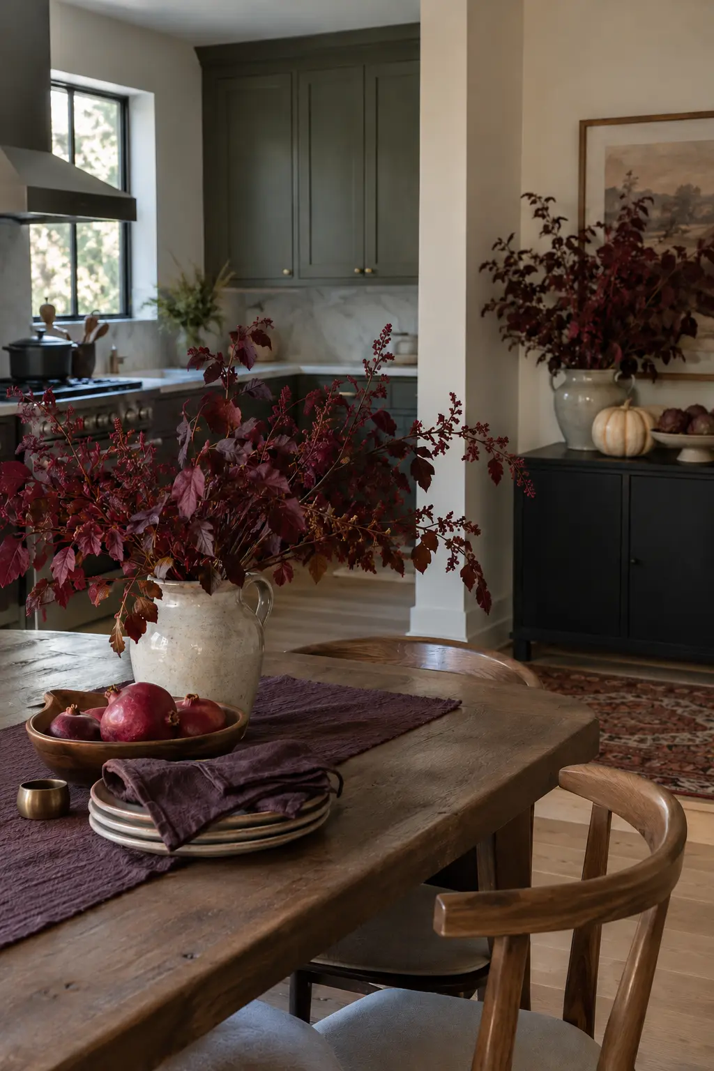 Thanksgiving kitchen styled with burgundy foliage, plum linens, and dark fruit