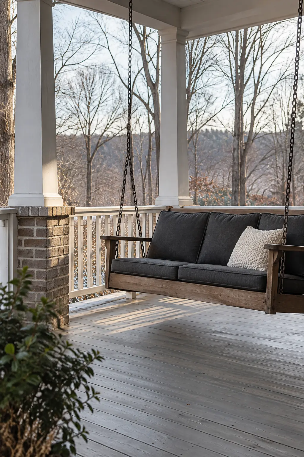 Covered porch with a dark suspended bench and a simple winter planter